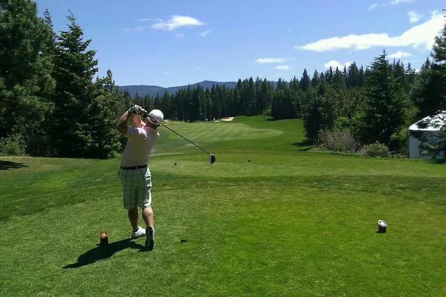 Golfer teeing off on a mountain golf course, representative image
