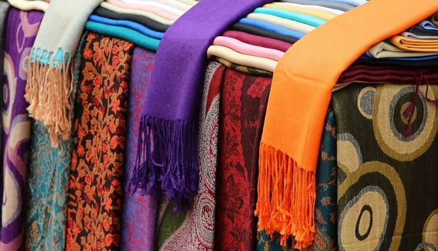 Stacked colorful Kashmiri pashmina shawls with paisley patterns